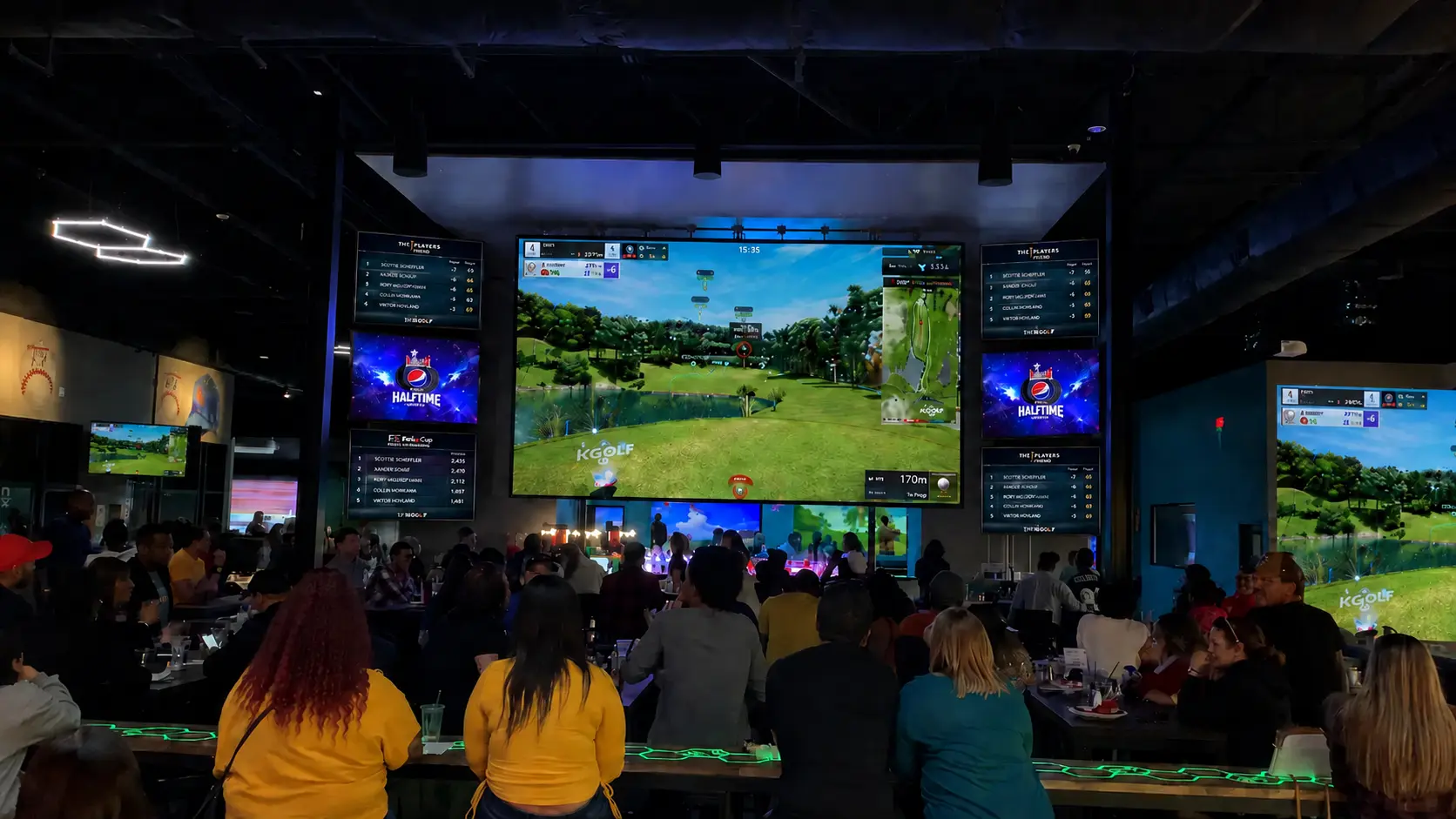 Indoor golf business branding venue with large simulator screens and guests